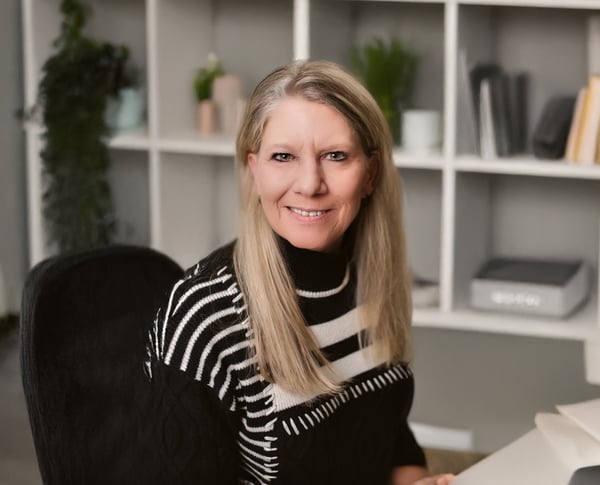 Zina Bartle, smiling at her desk in a modern office, brings decades of business consulting and sales leadership to her role as Ecosystem Navigator for East Central Indiana SBDC.