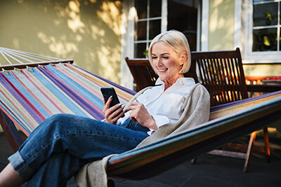 woman sitting outside in hammock looking at cell phone