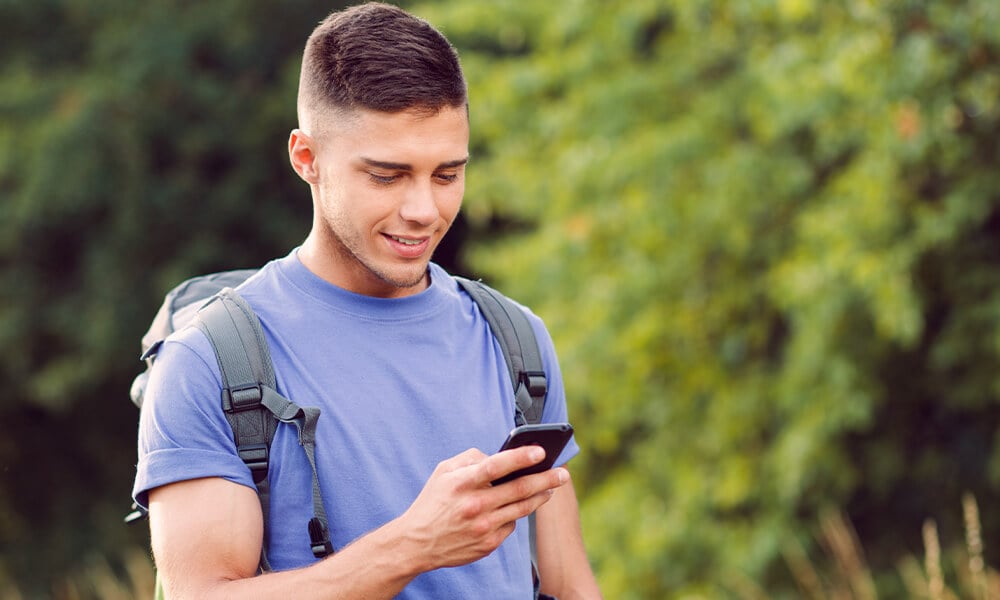 young man with a backpack looking at smartphone